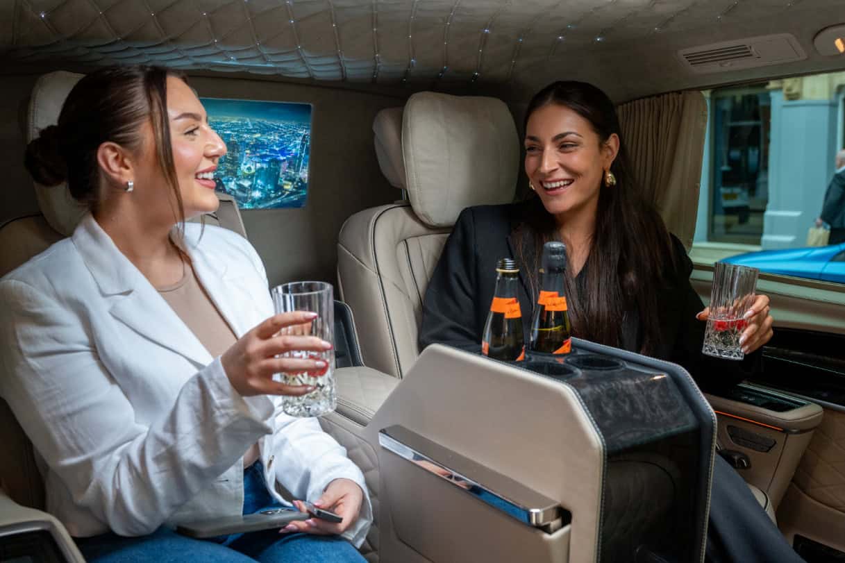 Luxury Travel in a Private Jet Two women enjoying drinks in a private jet interior for luxury travel.