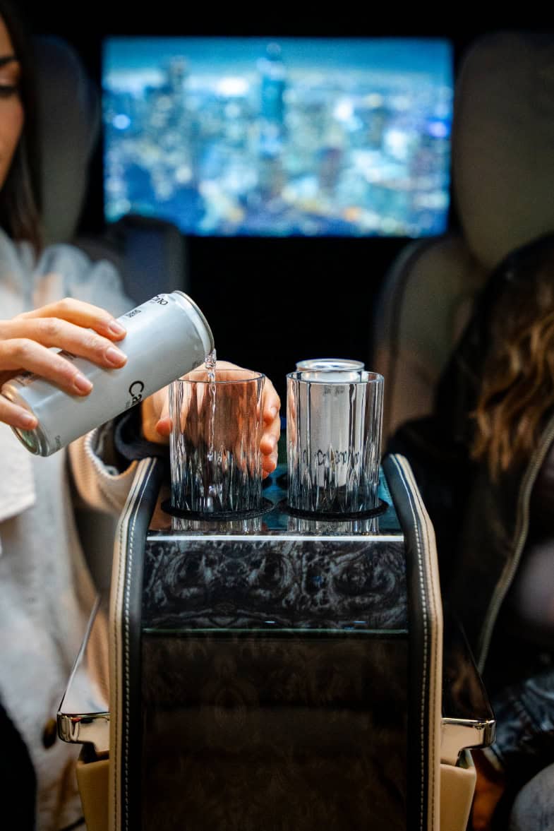 Swift Luxury Travel-26 Passengers enjoying drinks on a luxury flight with city views in the background.