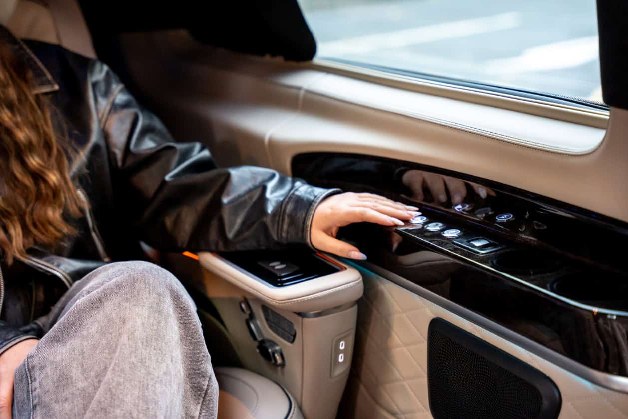 Swift Luxury Travel-28 Luxury travel interior with a passenger using a touchscreen control panel.