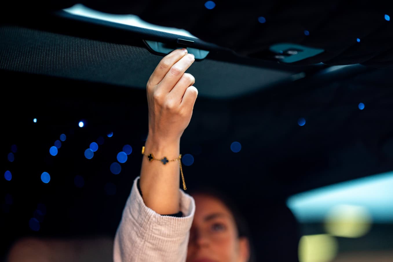 Swift Luxury Travel-55 Close-up of a woman adjusting the car's interior roof with a starry night background.