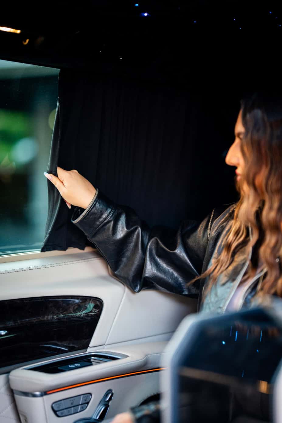 Swift Luxury Travel-57 Luxury woman adjusting window shade in private jet interior.